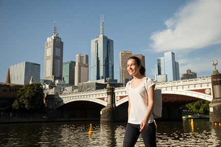 Student walking along river bridge